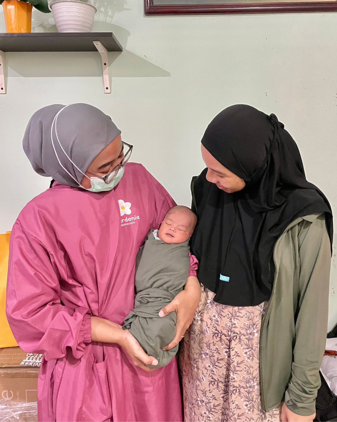 Gardenia midwife holding a baby beside the mother at home